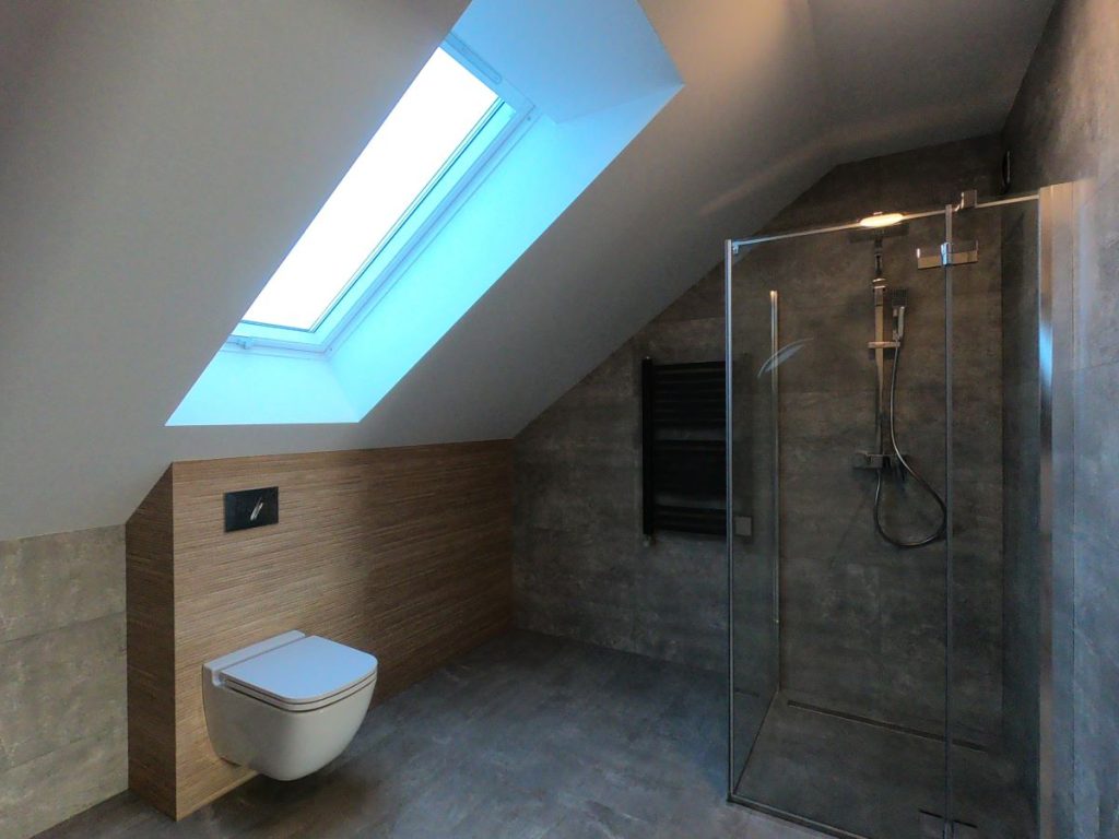 Nowoczesna łazienka na poddaszu ze skosami, prysznicem walk-in i szare płytki imitujące beton