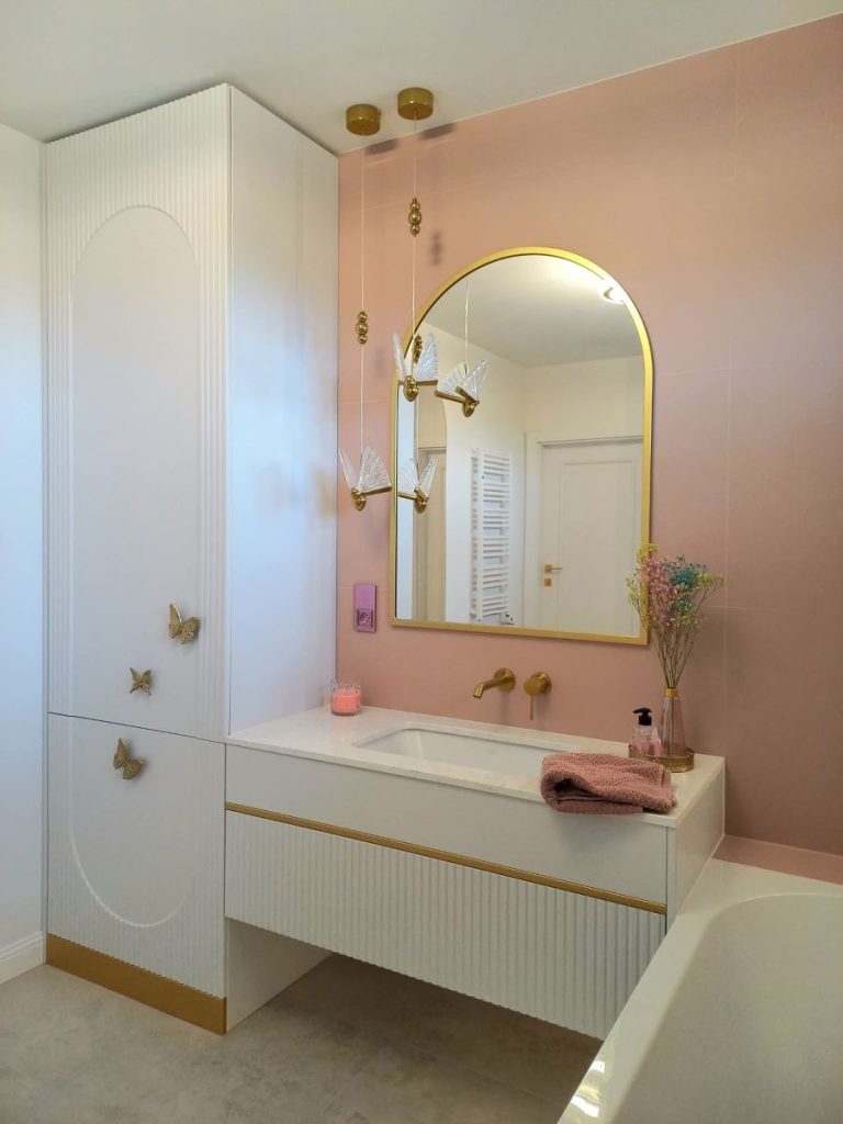 Nowoczesna łazienka w stylu glamour, układanie płytek imitujących marmur, lustro okrągłe LED, złota armatura i dodatki, szafka łazienkowa.