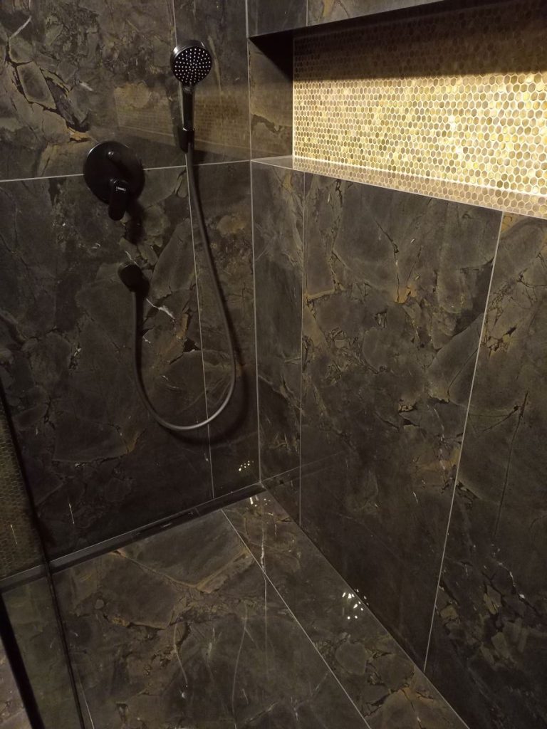 Łazienka glamour z czarnymi płytkami marmurowymi, złotymi dodatkami i oświetleniem LED